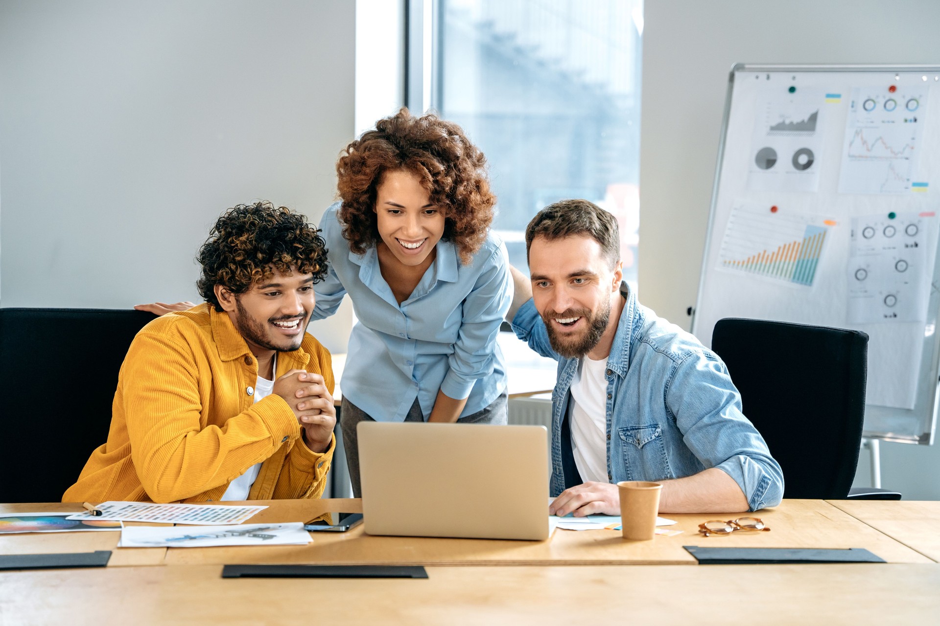 Partnership concept. Successful people of different nationalities, creative business team, working together on a project in a modern office, watching presentation, discussing ideas, brainstorming